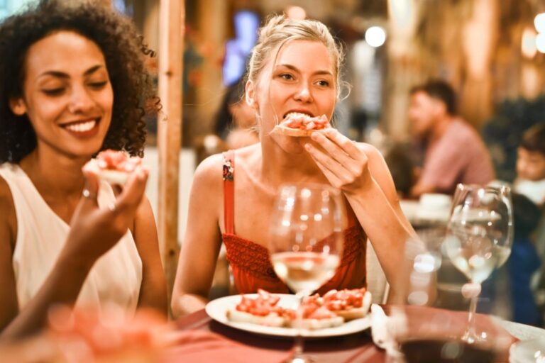 Two women sitting at a table eating food.