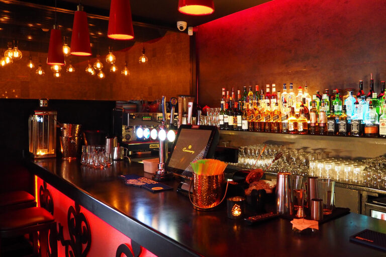 A bar with many bottles of alcohol on the counter