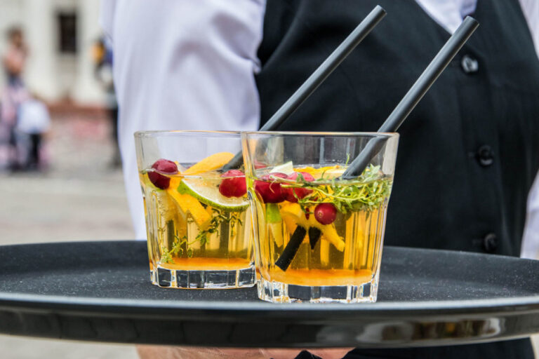 Two glasses of alcohol on a tray with straws.