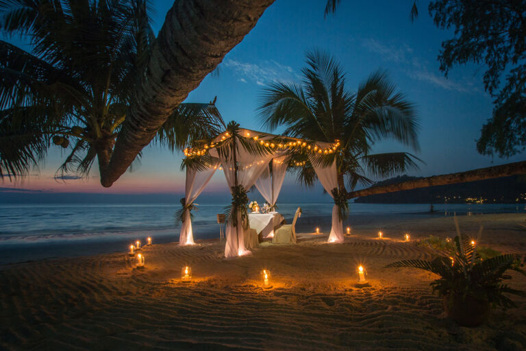 A couple sitting under a canopy on the beach