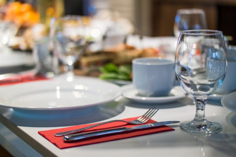 A table with plates, silverware and glasses on it.
