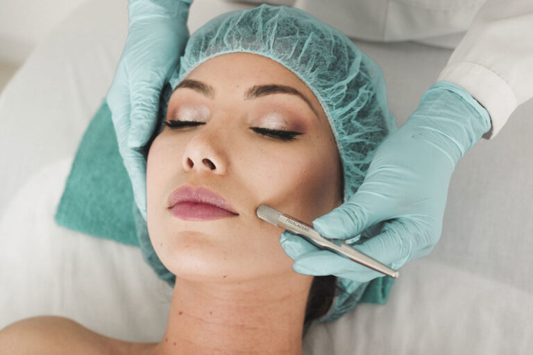 A woman getting her face waxed by two hands.
