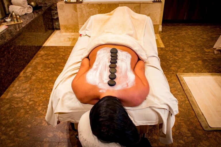 A woman laying on her back with stones in the middle of her body.