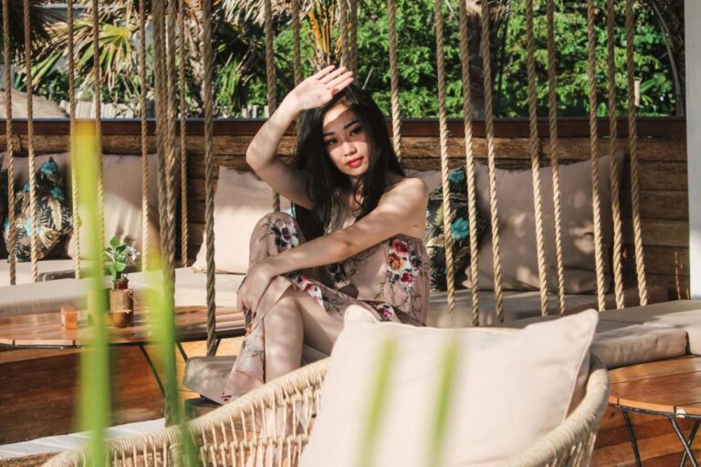 A woman sitting on top of a chair in front of some plants.