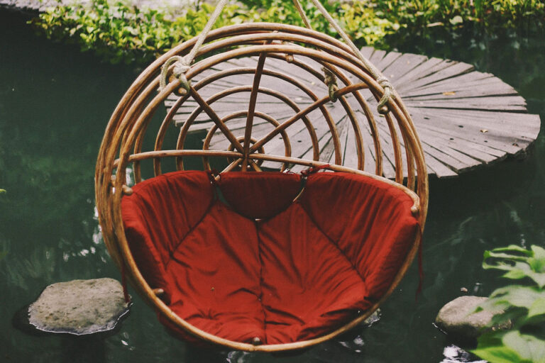 A red chair hanging from the side of a tree.