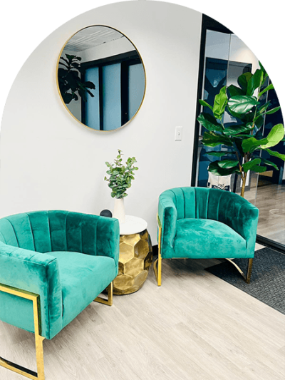 A room with two green chairs and a plant